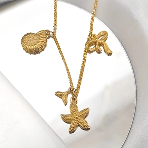 Detailansicht goldener Meeres-Anhänger mit Muschel-, Seestern- und Fischschwanz-Details
