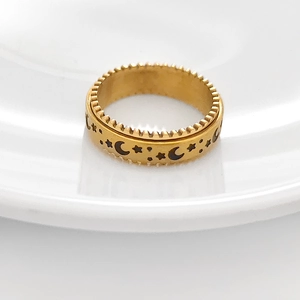 Detail of gold star and moon rotating anxiety ring with gear edges on white ceramic