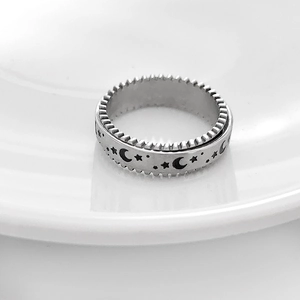Detail view of silver spinner ring with embossed moon and star patterns for stress relief