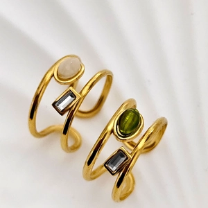 Macro view of gold plated winding rings with olive green and clear zircon gemstones
