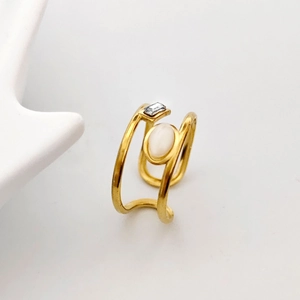 Close-up of gold open ring with an oval moonstone and a rectangular zircon inlay