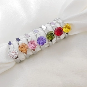 Primer plano macro de anillos de circonita de colores sobre tela de seda blanca