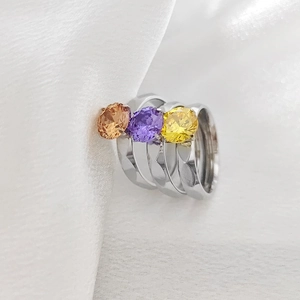 Detalle macro de tres anillos de acero inoxidable con circones redondos amarillos y violetas