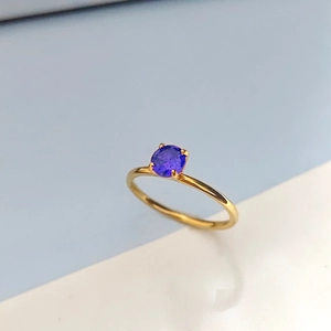 Detailansicht eines runden lila Zirkonrings mit klassischer goldener 4-Krallen-Fassung