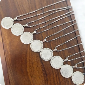Detail of silver round zodiac pendants with inlaid crystals and box chain on wood