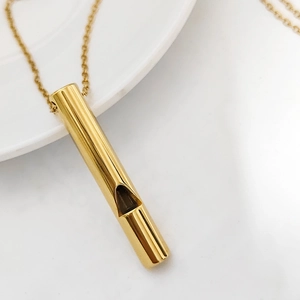 Close-up of polished gold whistle pendant on a fine link chain with mirror finish