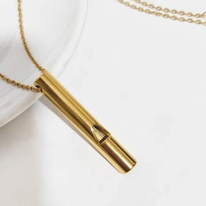 Minimalist gold whistle pendant necklace in polished stainless steel on white background