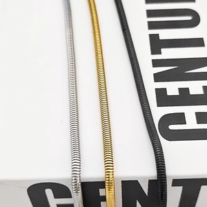 Gros plan de chaînes serpent en argent or et noir montrant une texture métallique lisse