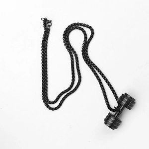 Détail d'un pendentif haltère noir avec une chaîne à mailles carrées assortie