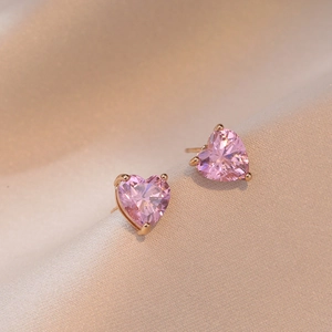 Detail van hartvormige roze zirkoon oorbellen met roségouden driepotige zetting