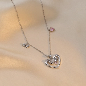 Collier argenté avec pendentif cœur rose et nœuds sur un fond en satin champagne