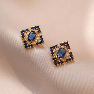 Boucles d'oreilles vintage dorées avec pierres bleu saphir sur tissu en soie rose