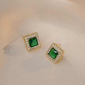 Elegante smaragdgrüne Zirkon-Ohrstecker in Halo-Quadrat-Form auf Seidenhintergrund vergoldet