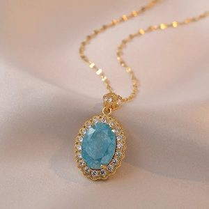 Elegant gold titanium necklace featuring oval blue zircon pendant with halo diamonds