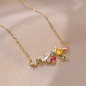 Collar dorado con colgante de circón multicolor brillante sobre fondo de satén lujoso