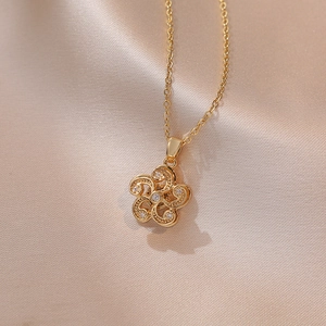 Gros plan du collier pendentif fleur dorée avec zircons sur un tissu en soie fine