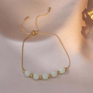 Detail van de verstelbare gouden kettingarmband met vijf groene lichtgevende kralen