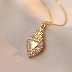Elegant gold heart pendant necklace with micro-pave zircons on champagne silk background