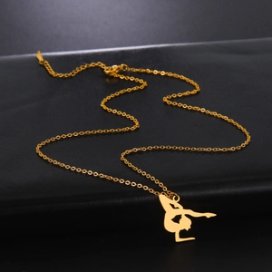 Detail of a gold gymnast pendant on a fine link chain against a black textured background