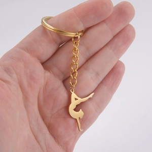 Golden gymnast silhouette keychain made of stainless steel held in hand for scale