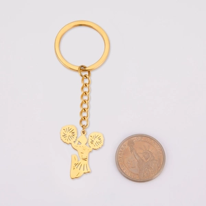 Golden cheerleader keychain with coin for scale showing polished alloy texture and detail