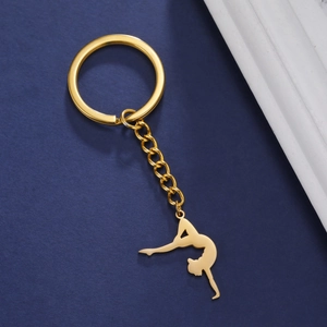 Detailed close-up of golden gymnast keychain silhouette on a deep blue background