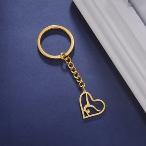 Détail d'un porte-clés cœur doré avec une silhouette découpée d'une gymnaste en équilibre