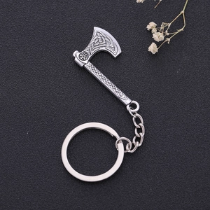 Detail of vintage silver axe keychain with Celtic knot patterns on a black background