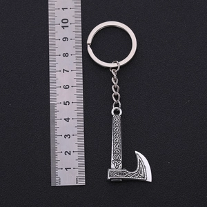 Viking axe keychain with Celtic engravings on black background showing scale with ruler