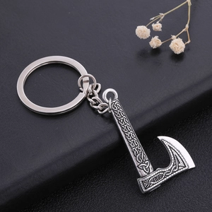Vintage silver Viking axe keychain with Celtic knot engravings on a black textured background