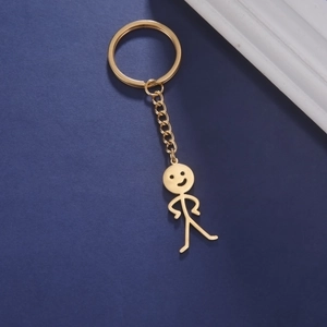 Détail d'un porte-clés doré avec pendentif bonhomme drôle sur fond texturé bleu foncé