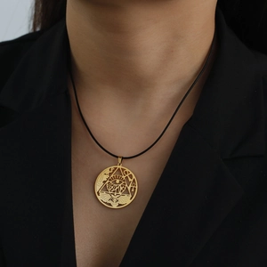 Close-up of golden Egyptian Eye of Horus and Ankh cutout pendant on black cord necklace