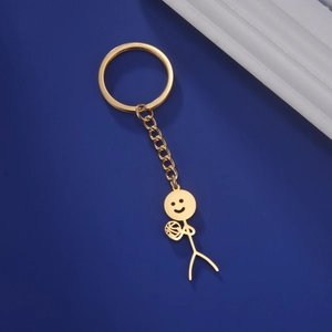 Detailed view of a gold-plated stickman keychain holding a mini basketball on blue background