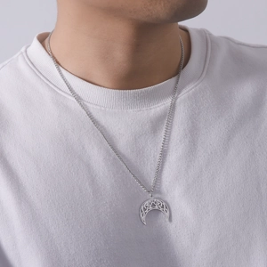 Detail of silver crescent moon pendant with镂空 cat paw pattern worn on a white t-shirt