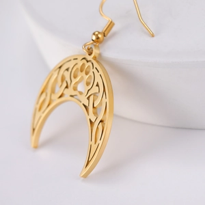 Detail of 18K gold plated moon pendant earring with hollow Celtic knot and paw print