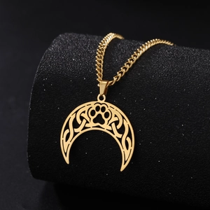 Detailed macro shot of golden moon pendant with Celtic knot and animal paw print on black stand