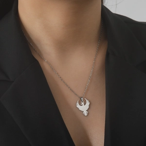 Close-up of a silver phoenix pendant with cutout details worn on a black suit jacket