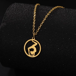 Détail d'un pendentif yoga en or avec silhouette de gymnaste sur collier minimaliste