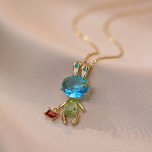 Détail d'un pendentif lapin doré serti de pierres précieuses bleues, vertes et rouges