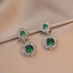 Macro detail of silver floral earrings with emerald green zircon and colorful accents