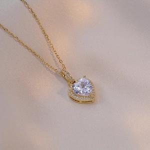 Macro shot of gold heart pendant necklace featuring large zircon and halo diamond setting