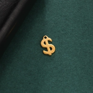 Détail macro du pendentif dollar doré en acier inoxydable sur une surface vert foncé