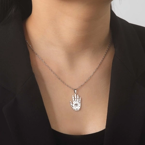 Close-up of minimalist silver Hamsa Hand pendant with crescent moon and star motifs