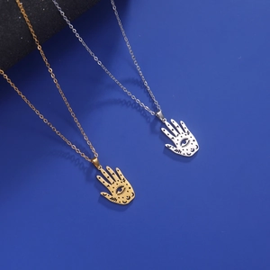 Detail of gold and silver Hamsa hand pendants with moon and star engravings on necklaces