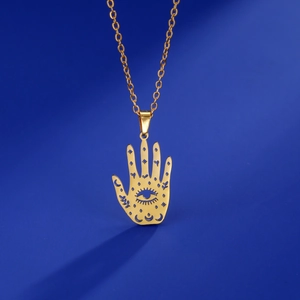 Close-up of golden Hamsa hand pendant with moon and star hollow patterns on blue background