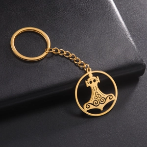 Close-up of golden Thor’s hammer Mjölnir keychain with Celtic knot engravings