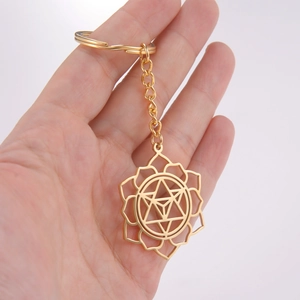 Golden stainless steel lotus geometric hollow pendant keychain on a plain grey background