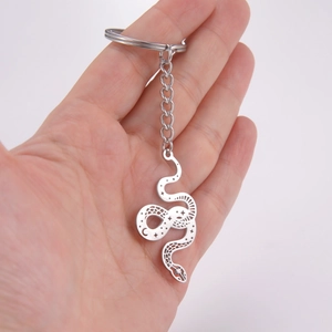 Detail of silver snake keychain featuring hollow moon and star patterns in hand