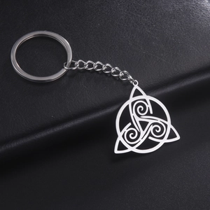 Polished silver stainless steel Triskelion pendant keychain on dark leather background