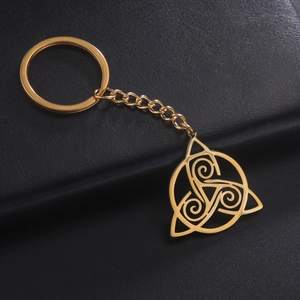 Detailed close-up of golden Triskele Celtic knot keychain on a black leather background